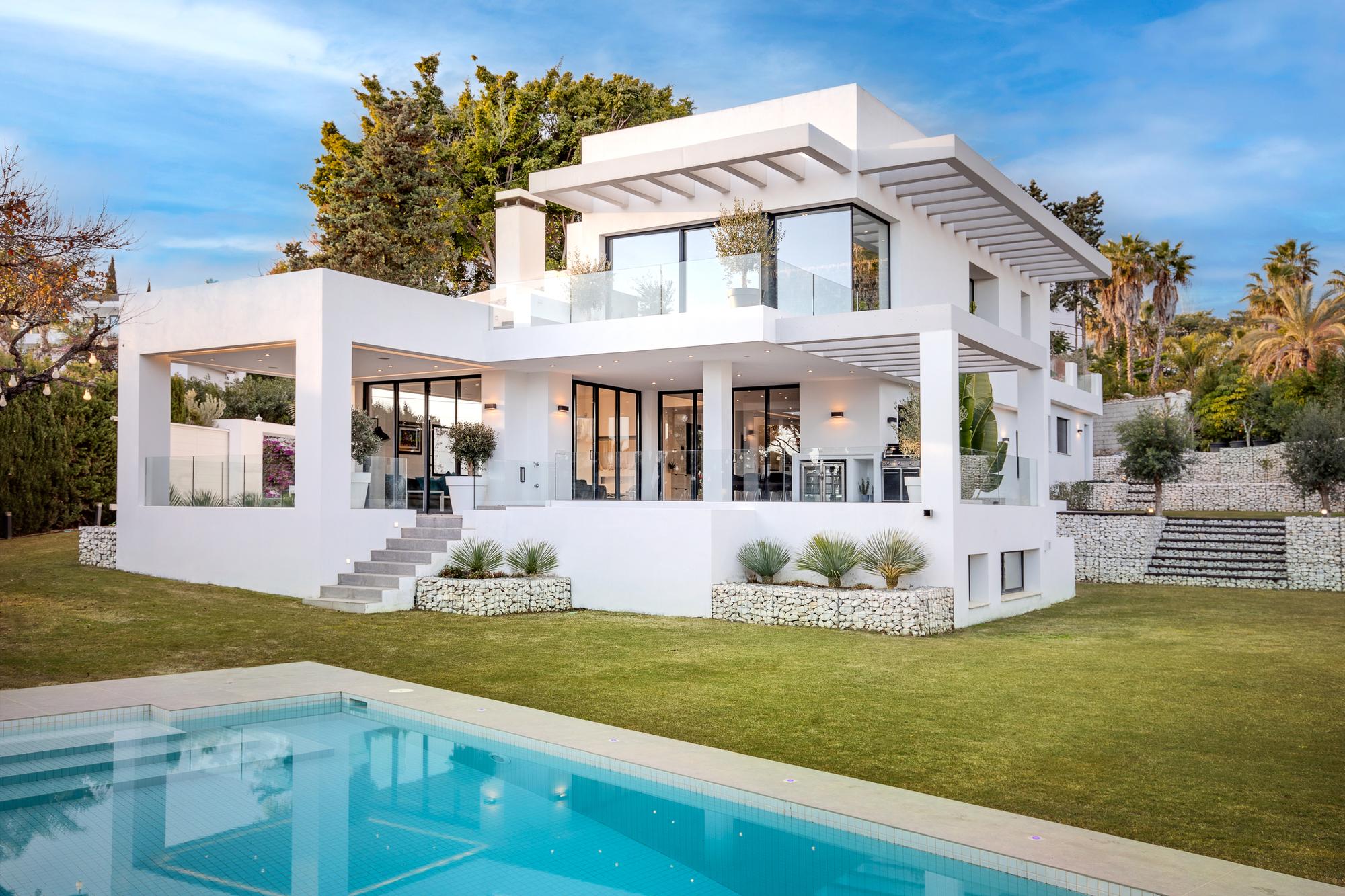 Casa Amigos vista desde la piscina, con las terrazas y pérgolas hacia el jardín