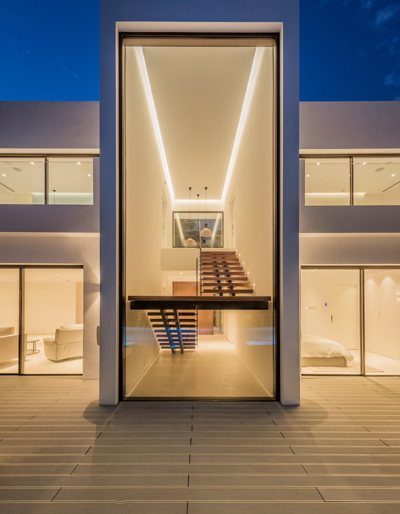 Entrance of Villa El Pilar lit at night, with the staircase beyond